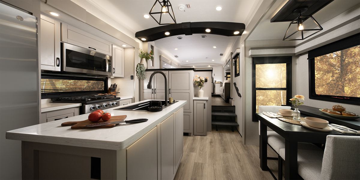 Inside a luxury fifth wheel: kitchen island, full cooker and dining nook, set up and ready at the event