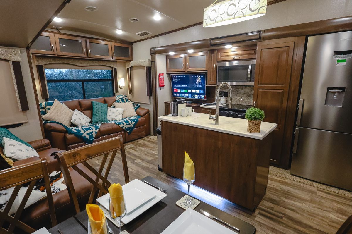 Living area of the Cedar Creek fifth wheel: leather sofas, kitchen island and TV